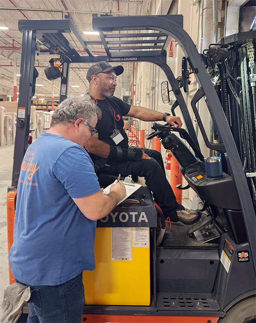 Thielen consults with forklift driver on warehouse work.