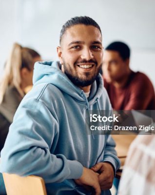 Happy college student having a lecture in the classroom and looking at camera. Happy college student having a lecture in the classroom and looking at camera.